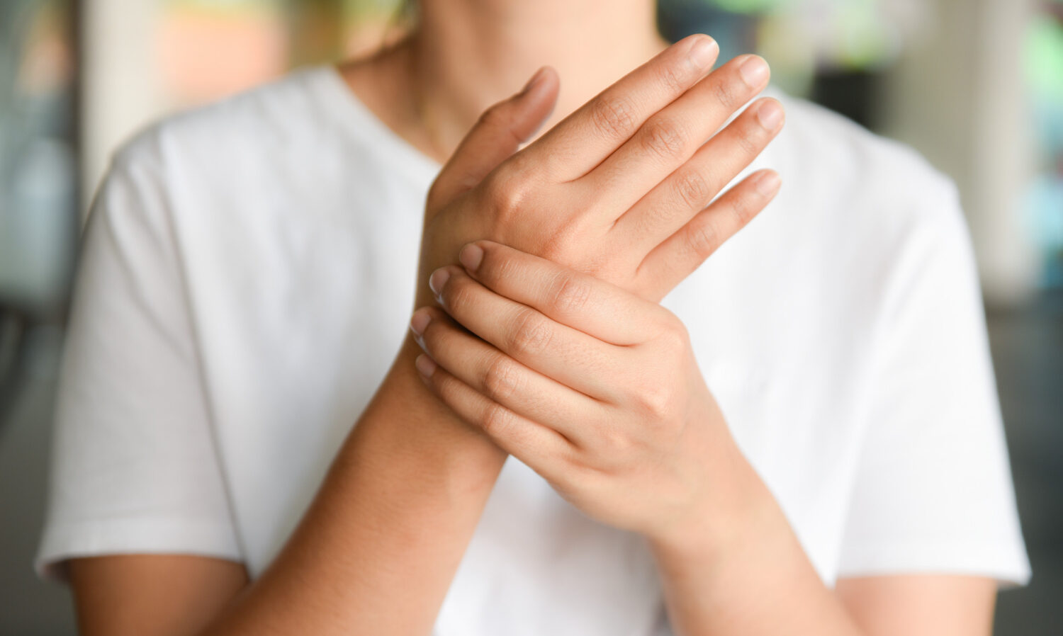 Person wearing a white shirt with hands pressed together in front of their chest (clasped, as in a gesture of prayer or contemplation).